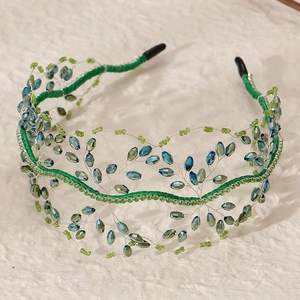 Close-up of handmade bridal headband with blue crystal beads and green leaf accents