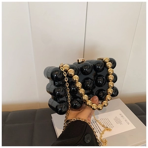 Close-up of black acrylic dinner bag with spherical texture and gold chain straps