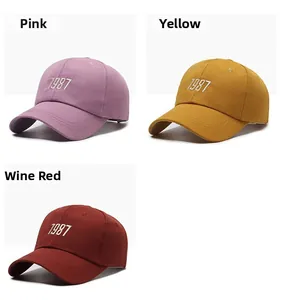 Detailed views of cotton baseball caps with 1987 embroidery in pink, yellow, and burgundy