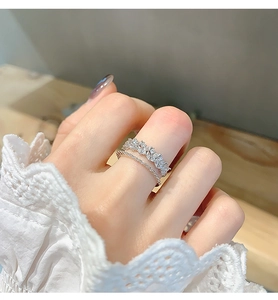 Detail of a layered silver ring featuring zircon flower petals and a sparkling band
