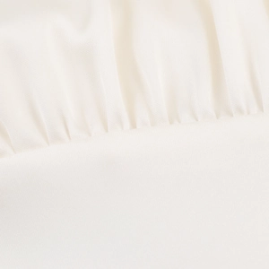 Macro shot of white satin blouse fabric showing detailed pleated texture and weave