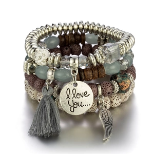 Detail of bohemian multilayer bracelet featuring wing pendant and gray tassel charms