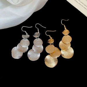 Detail of gold and silver long tassel earrings with irregular matte hammered finish