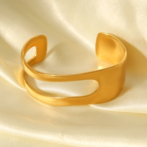 Detail of 18K gold-plated asymmetrical cuff bracelet on smooth beige silk fabric