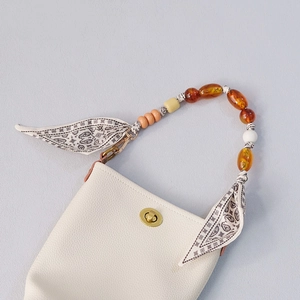 Detail view of cream leather phone bag with beaded chain and paisley scarf wrap strap