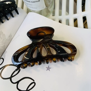 Amber tortoise shell flower hair claw clip displayed on a minimalist white magazine