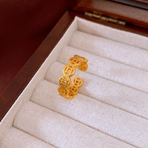 Détail d'une bague ouverte en or mat motif pièce de monnaie dans un écrin de luxe