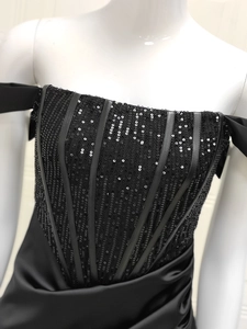 Gros plan du bustier à paillettes noires et détails de satin plissé sur la robe