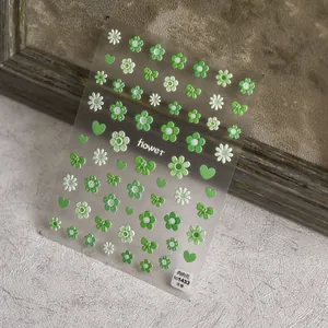 Macro detail of 5D embossed nail stickers featuring green daisies and ribbon patterns