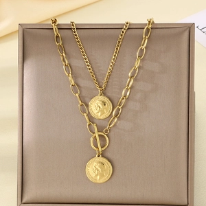 Macro detail of gold layered necklace with vintage coin pendants and toggle clasp closure