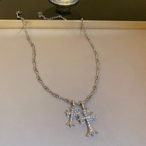 Silver cross necklace with sparkling rhinestones on a minimalist jewelry tray display
