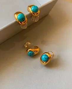 Macro detail of 18k gold plated turquoise stud earrings with natural black mineral veins