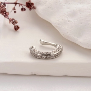 Macro detail of silver-toned ear cuff with micro-p鑲ed cubic zirconia on stone background
