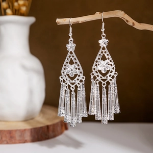 Close-up of ethnic silver peacock earrings with leaf hollow patterns and long tassels