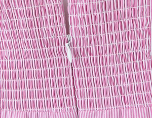 Close-up of pink and white striped smocking fabric with a hidden zipper detail