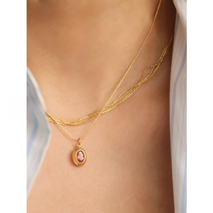 Detail of a vintage layered gold-plated necklace with a red oval gemstone pendant