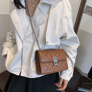 Elegant brown quilted chain shoulder bag worn with a casual outfit by a model