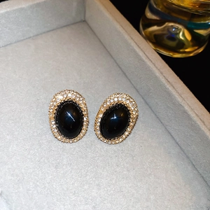 Close-up of vintage black oval earrings with gold frames and sparkling rhinestones