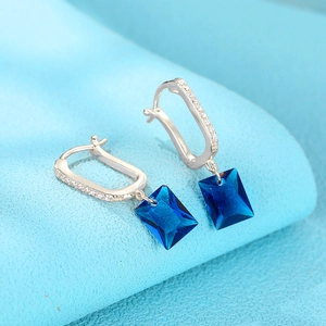 Detailed close-up of U-shaped silver earrings with sparkling blue rectangular crystals
