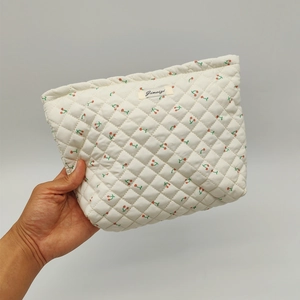 Detailed close-up of quilted floral cosmetic bag with red cherry prints and cotton texture