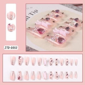 Detail of pink press-on nails featuring silver glitter, purple heart gems, and 3D bows