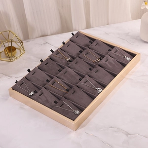 Macro detail of jewelry display tray with 20 slots in gold metal and grey velvet lining