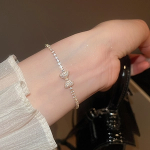Close-up of elegant gold tennis bracelet featuring a sparkling crystal bow pendant on wrist