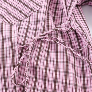 Gros plan sur le tissu à carreaux rose et marron montrant le détail du nœud de taille