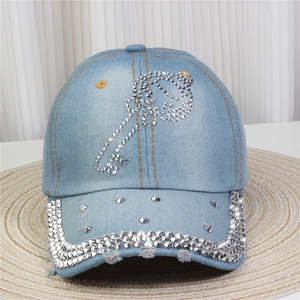 Vue détaillée du motif clé en strass sur casquette en jean bleu clair délavé