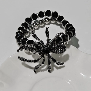Gothic punk black spider pendant bracelet with faceted beads on white shell tray