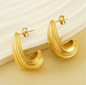 Detailed macro view of gold-plated ribbed hoop earrings with C-shaped geometric design