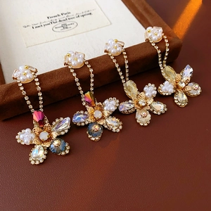 Close-up of gold-plated flower earrings with faux pearls and colorful crystals