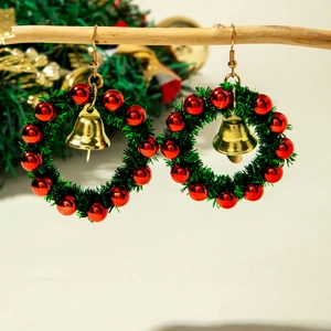 Macro detail of Christmas wreath earrings with red beads and golden bell on wood branch