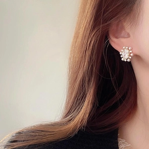 Elegant gold-plated flower stud earrings with zircon and pearls on a model ear