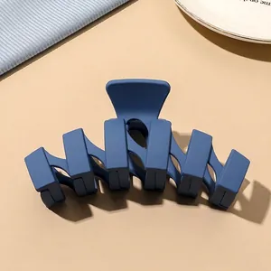 Close-up of matte dark blue geometric hair claw clip with a modern minimalist design