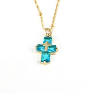 Macro shot of sky blue zircon cross pendant with gold chain and rectangle cut stones