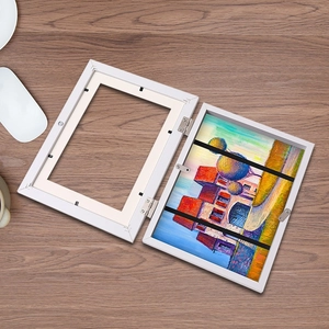 White folding art frame for kids drawings with dual frame hinges and a colorful landscape