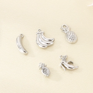 Macro detail of silver stainless steel banana and pineapple charms with crystal inlay