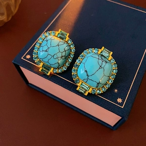 Close-up of vintage gold square earrings with turquoise stones and blue crystals detail