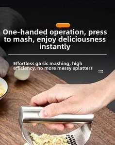 Macro shot of manual stainless steel garlic press mincing cloves on a wooden board
