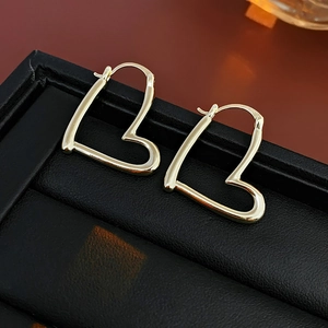 Gros plan de boucles d'oreilles créoles coeur en or poli sur présentoir noir texturé