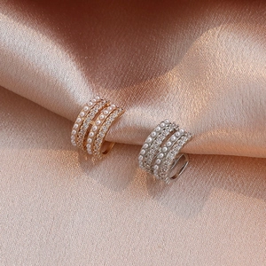 Multilayer gold and silver ear bone clips with pearls and rhinestones on beige satin