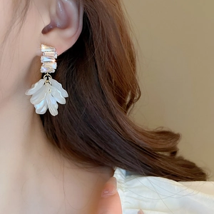 Close-up of gold-plated shell flower tassel earrings with zircons on a model's ear