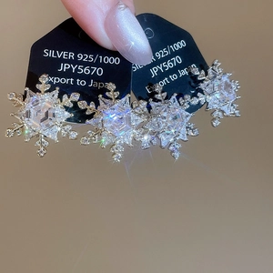Macro shot of 925 silver snowflake stud earrings with sparkling zircon crystals
