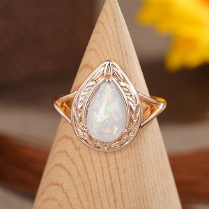 Makroansicht des Opals im Birnenschliff mit aufwendig geschnitztem Band auf Holzständer