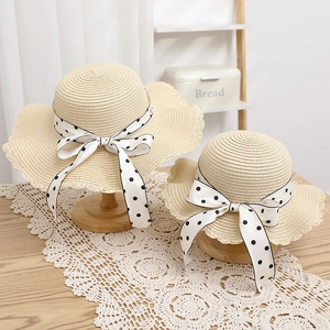 Detail of parent-child straw sun hats with polka dot bows and wavy lace edges