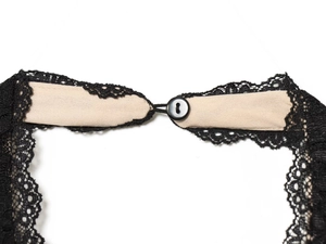Detail of black lace trim and button closure on a beige backless halter dress