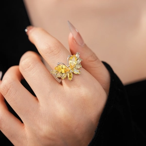 Gros plan détaillé d'une bague papillon argentée avec zircons champagne au doigt