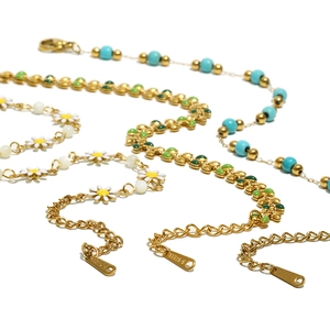 Stack of 18K gold plated stainless steel daisy bracelets with green enamel and turquoise beads