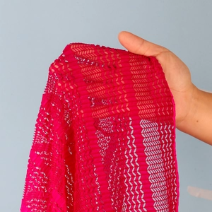 Dettaglio di tessuto pizzo fucsia traforato con motivo ondulato e trama a maglia fine